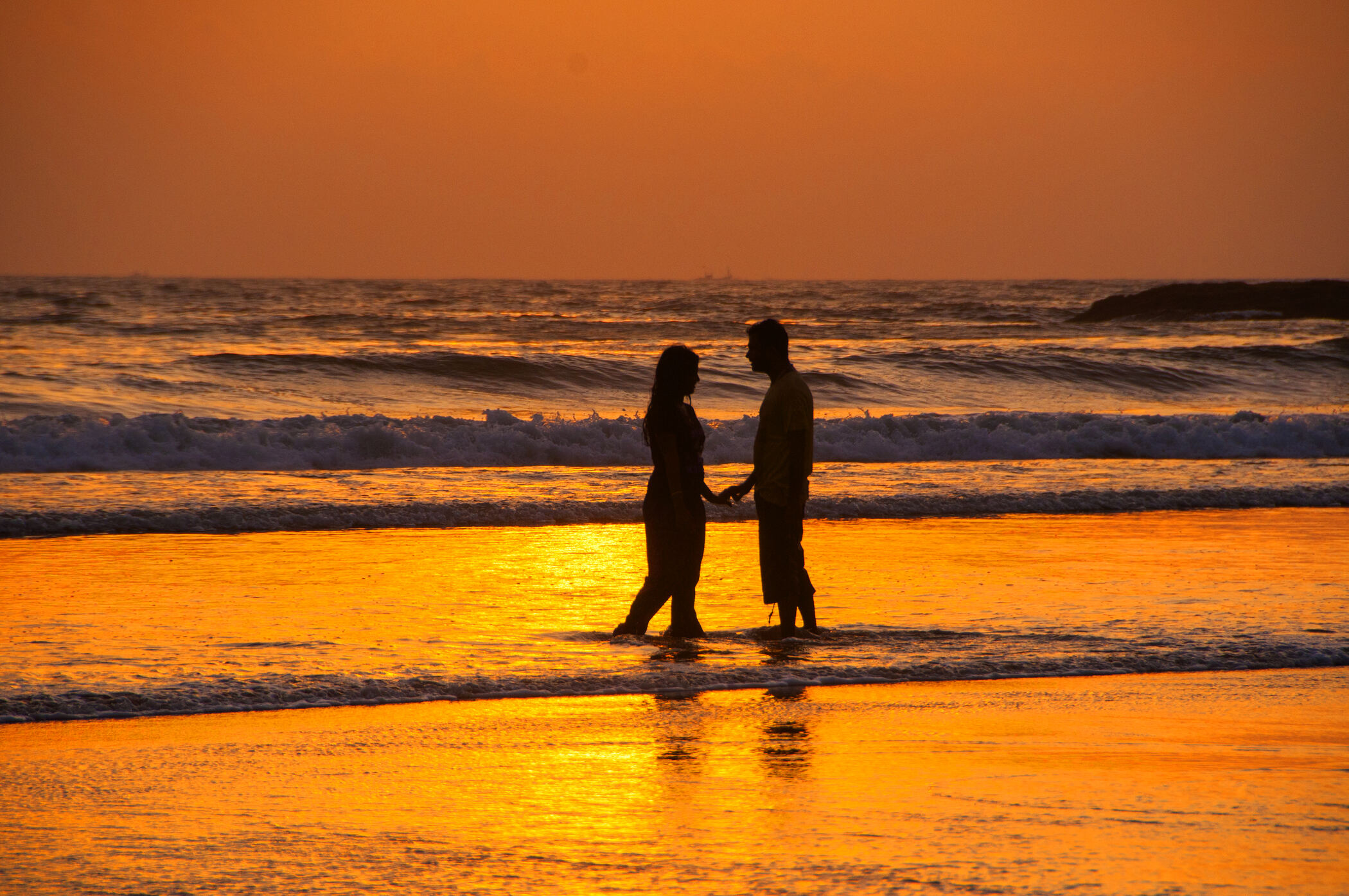 A couple hand in hand watching the sunset together